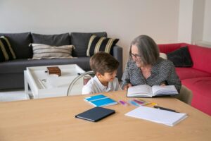Elderly woman teaching her young grandson at home, sharing a joyful educational moment.