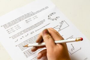 A student in Islamabad solves an A-Level Maths past paper with a tutor's guidance.
