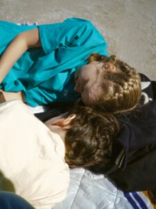 Two children resting on a blanket under the sun in Montréal, Quebec, Canada.