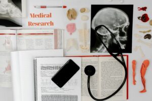 An open biology book next to a stethoscope and a page of handwritten medical notes, symbolizing science and medical tutoring.