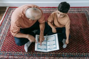 A father and son sharing a reading moment on a Persian rug, focusing on learning and bonding.